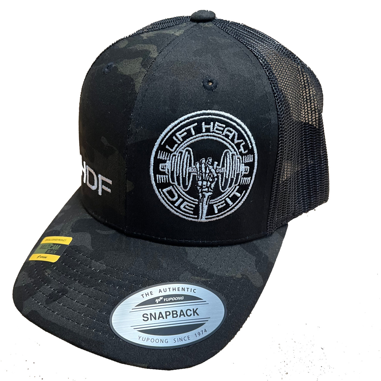 Lift Heavy Die Fit embroidered camo trucker cap left side view showing mesh back panel and plastic snapback closure for gym wear